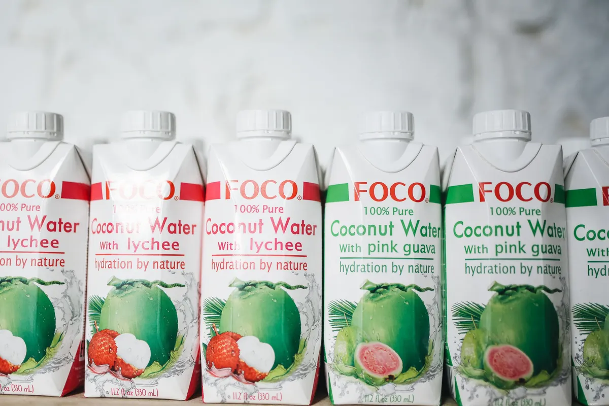 Row of printed drink cartons with screw caps lined up on a white shelf