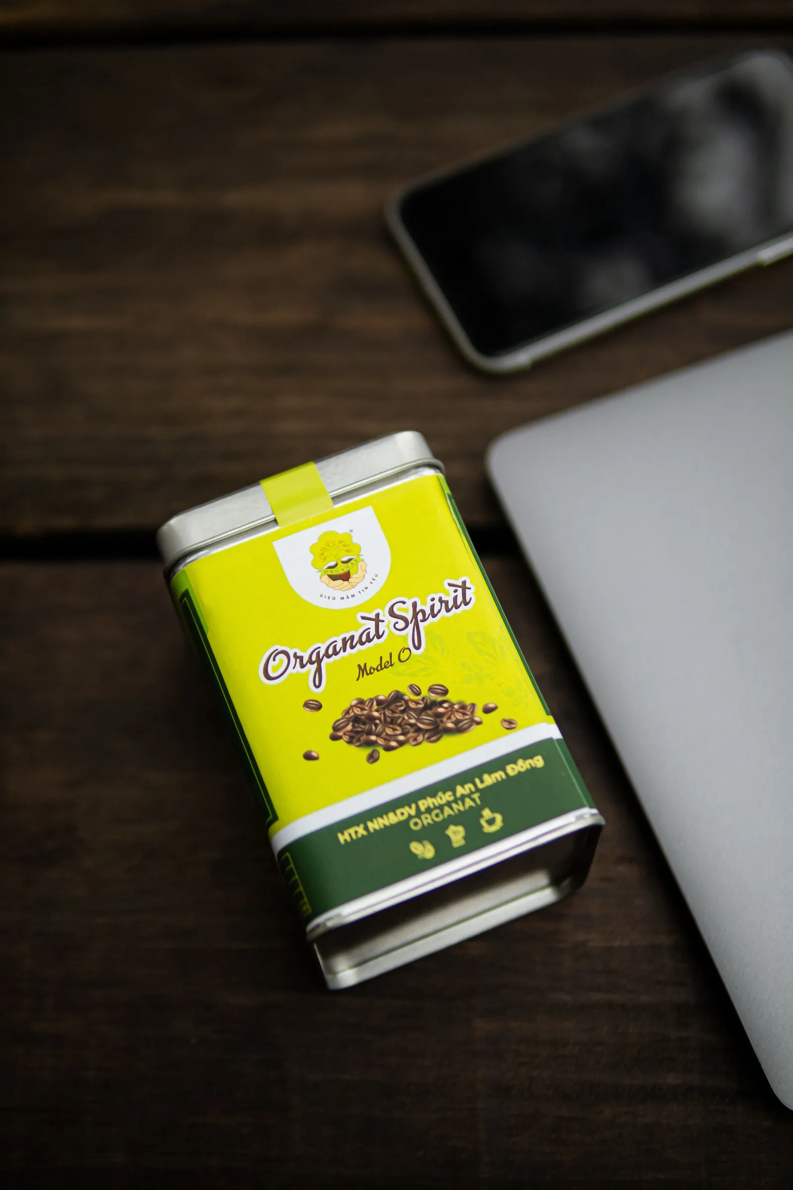 Printed coffee tin on a dark desk beside a laptop