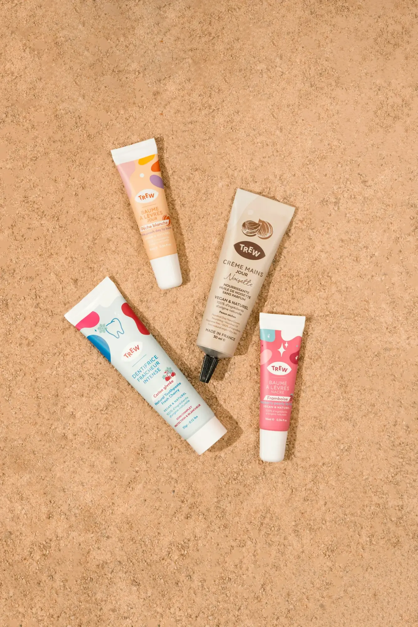 Four printed cosmetic squeeze tubes on a cork background