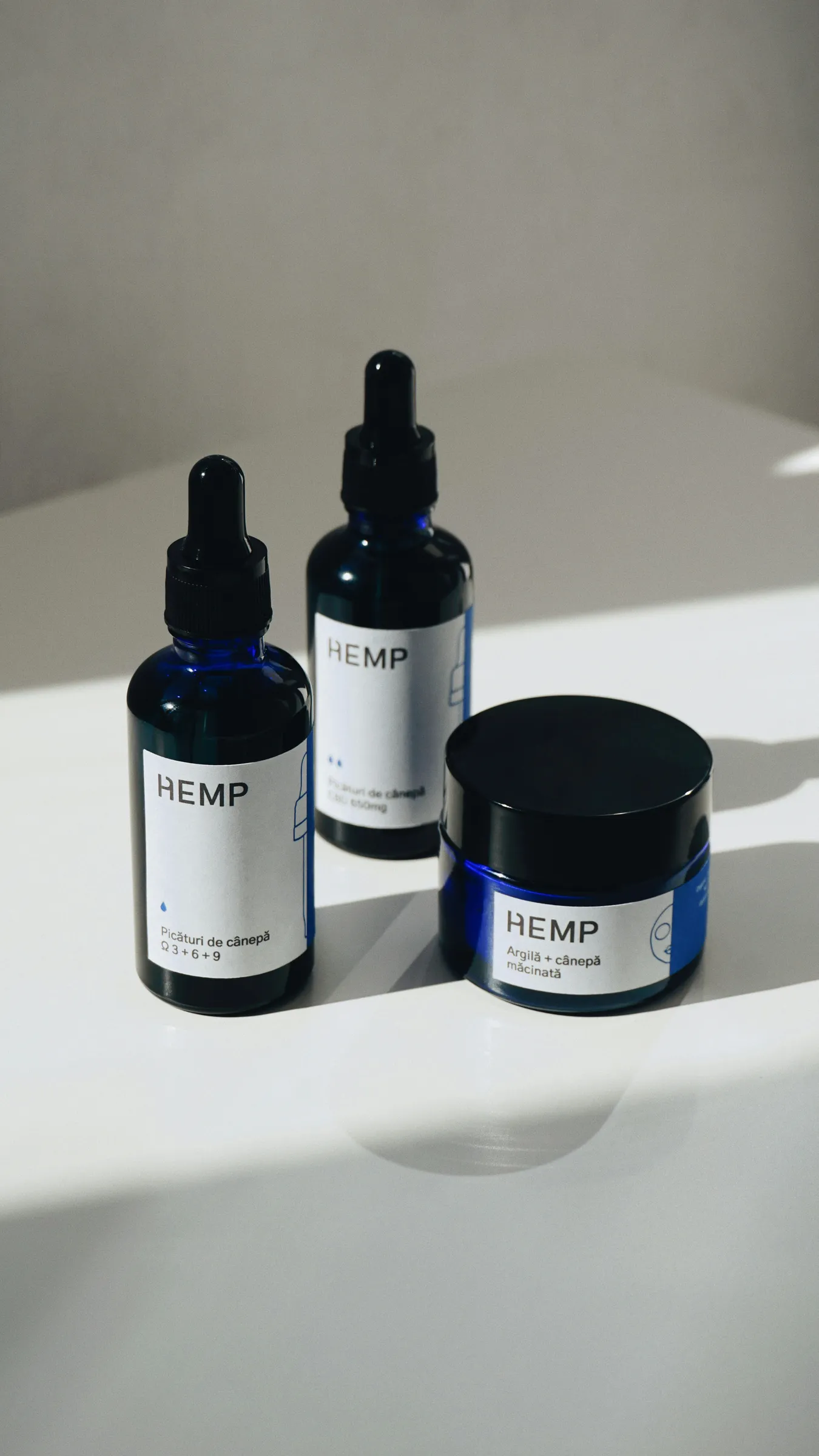 Navy dropper bottles and a jar with white labels for hemp skincare