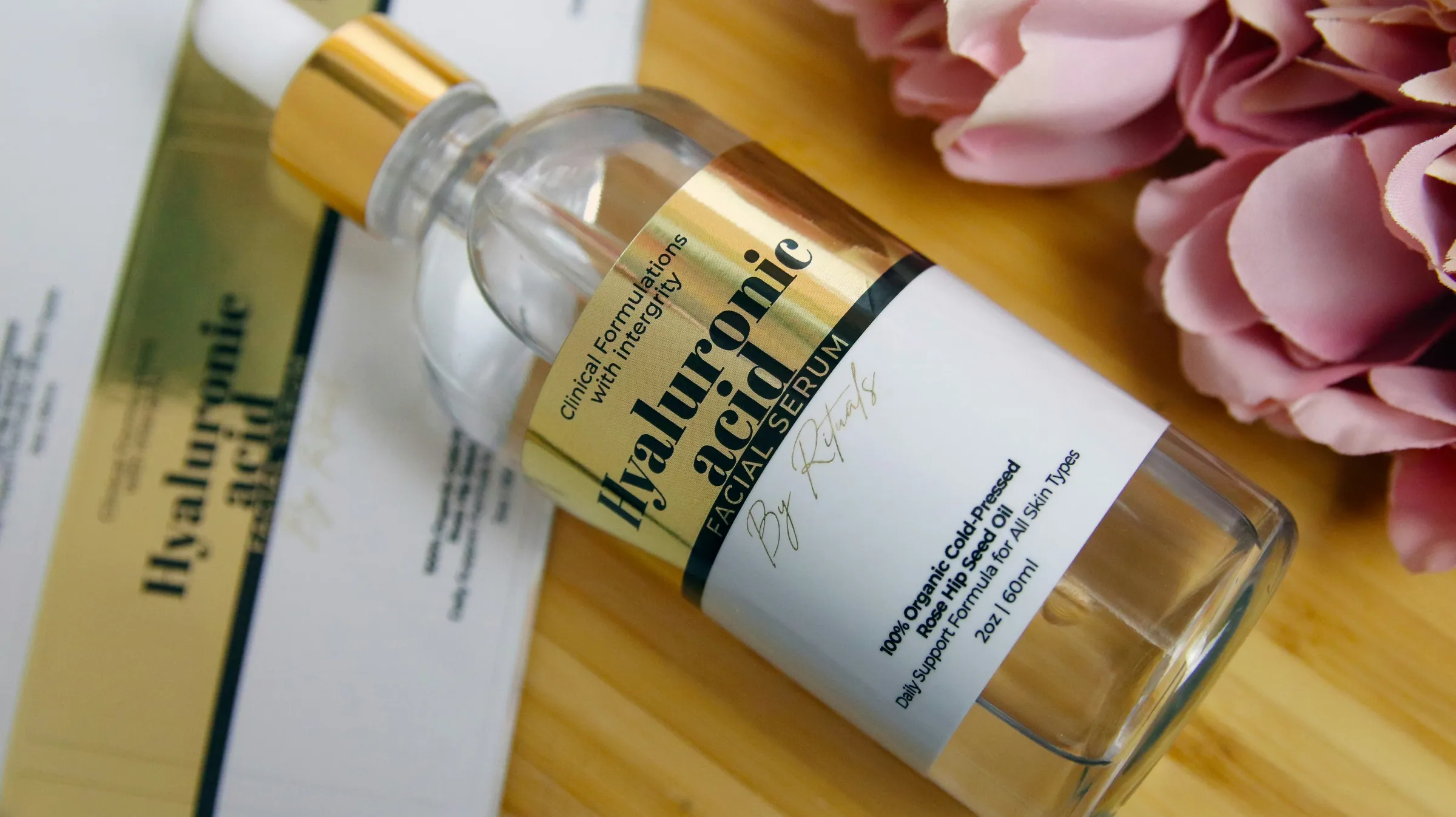 Glass serum bottle with a gold and white label lying on wood