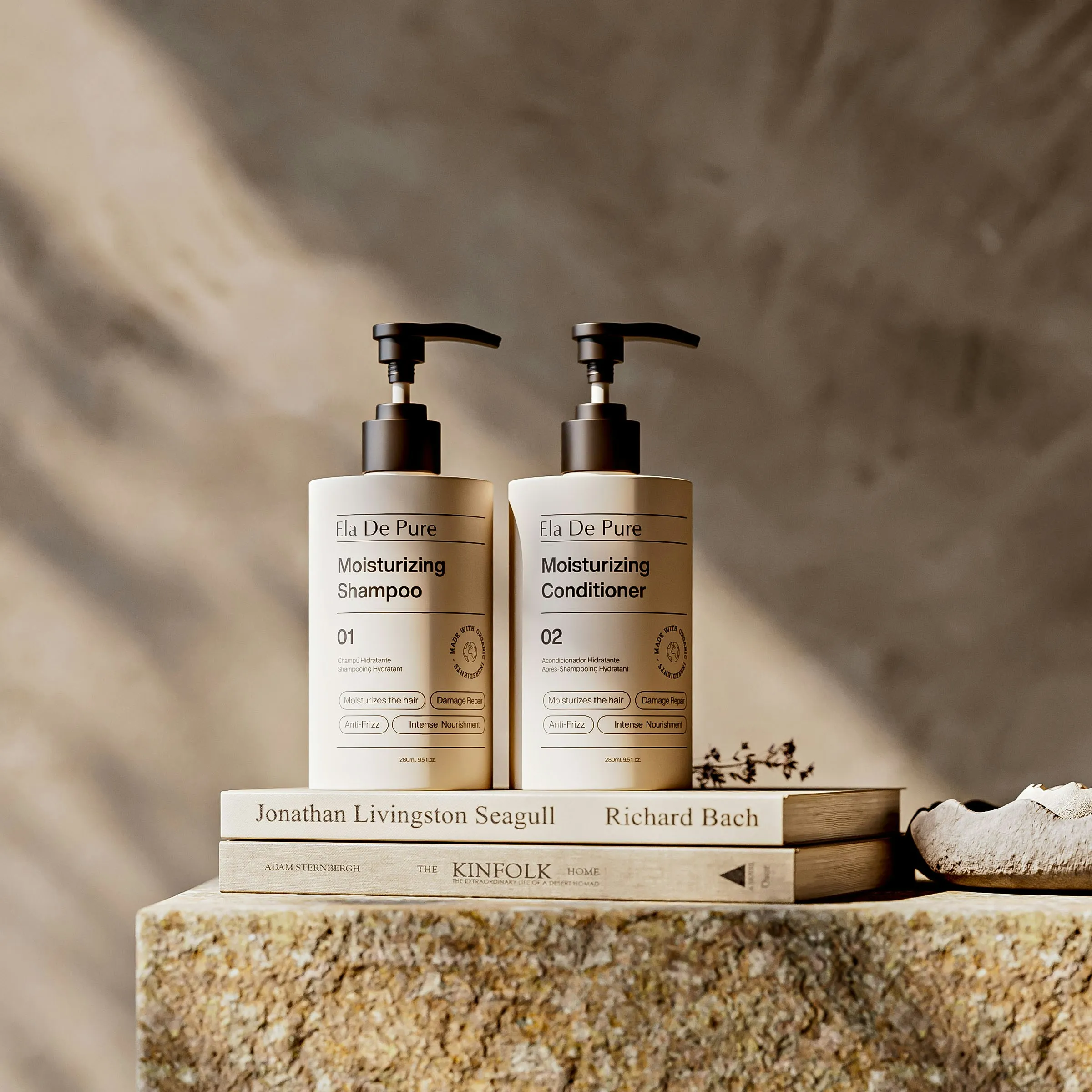 Matching shampoo and conditioner pump bottles with cream labels on stone