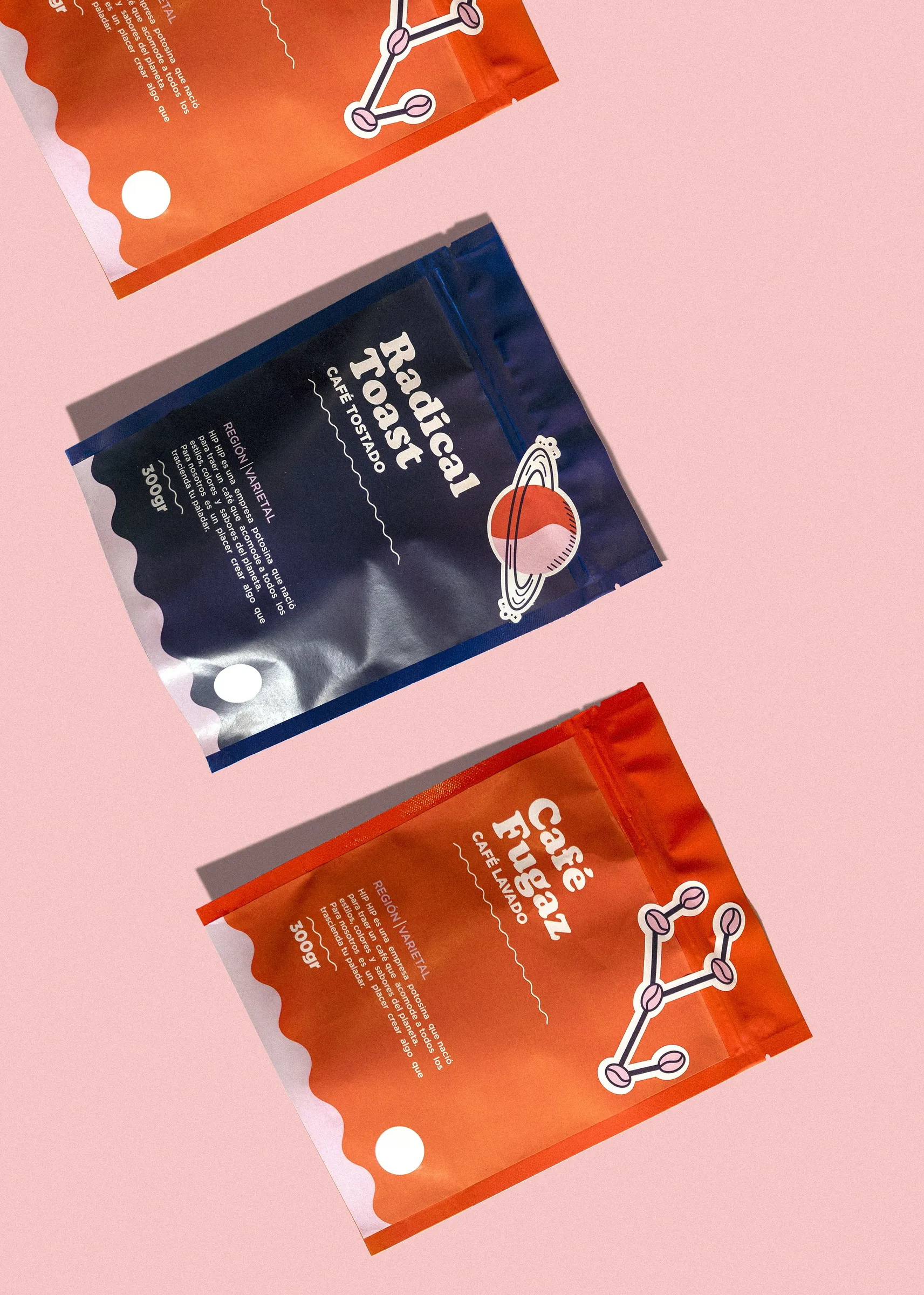Three printed stand-up coffee pouches in navy and orange on a pink background