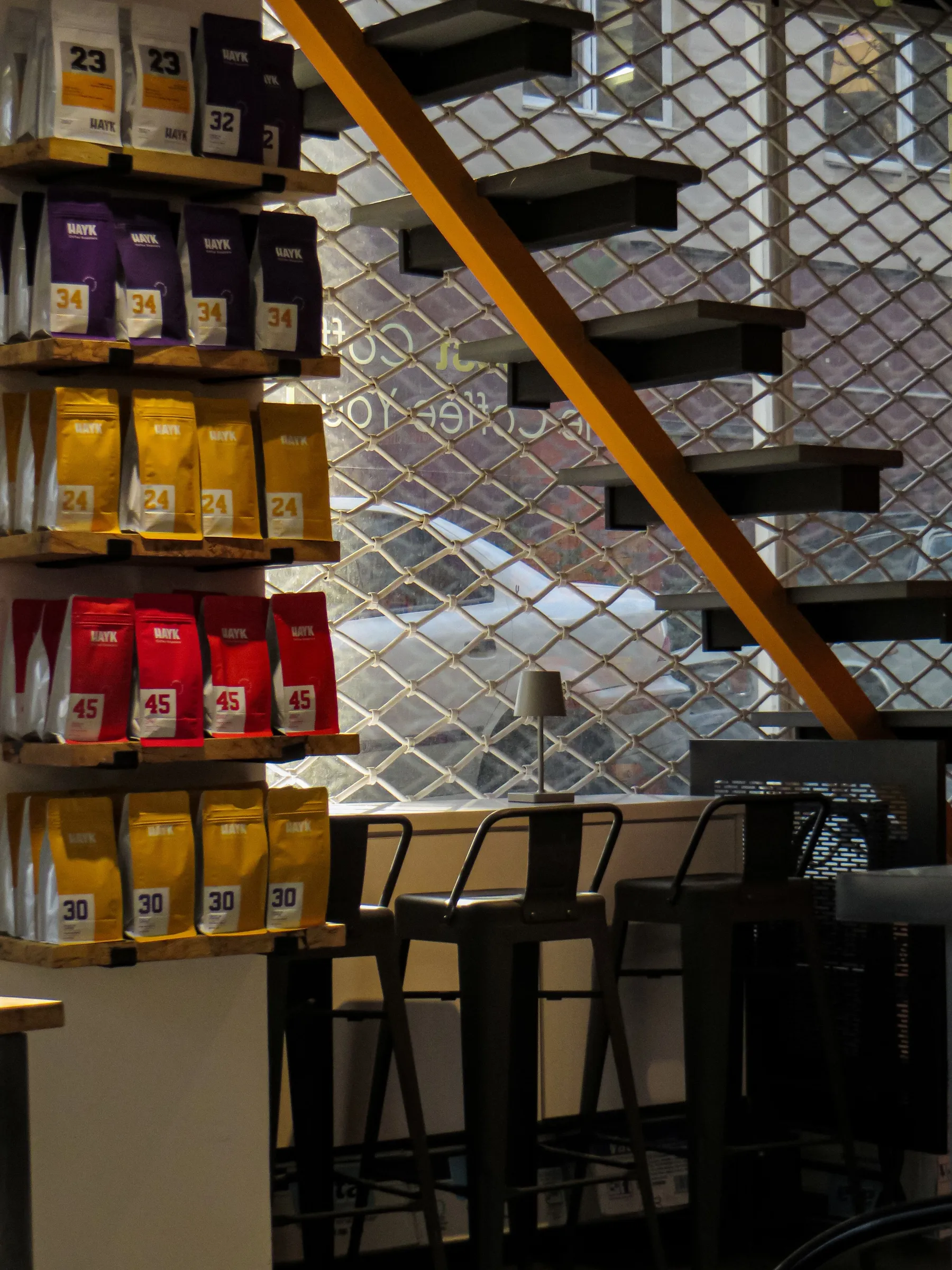 Coffee shop wall shelving stacked with colour-coded printed coffee bags in numbered rows