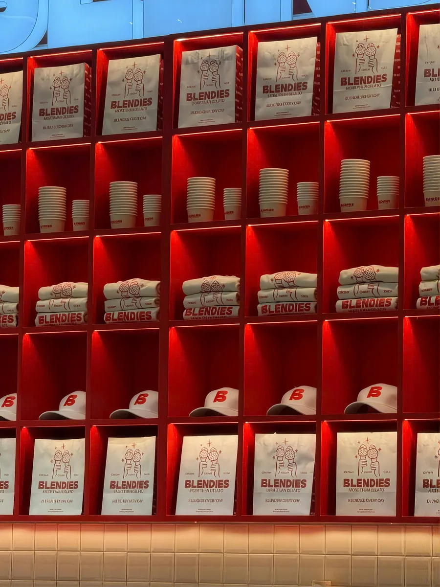 Red-lit retail wall display stacked with printed coffee bags and cups
